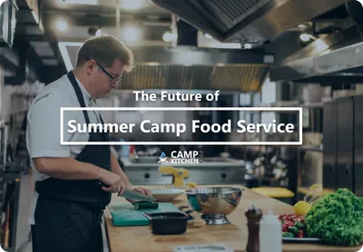 A chef plating food at the pass in a commercial summer camp kitchen.